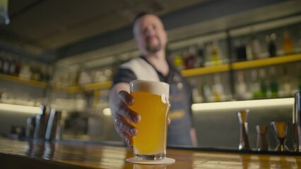 Caucasian bartender puts a glass of beer on the counter and a man's hand takes it away. A party in a pub, watching football with beer and friends. High quality 4k footage