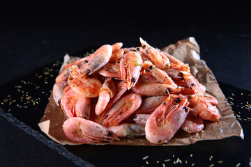 Boiled shrimp. Appetizer for beer. Serving boiled shrimp. Boiled shrimp on parchment. Photo on black background. Menu for bars.