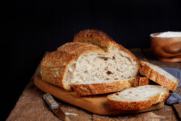 Rustic sourdough bread with cut slices on a wooden table. 