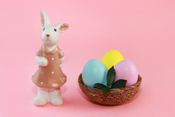 Ceramic figurine of a bunny in a dress and colorful Easter eggs in a plate