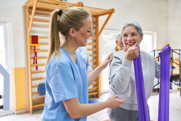 Fototapeta premium Therapist assisting senior woman doing workout at nursing home