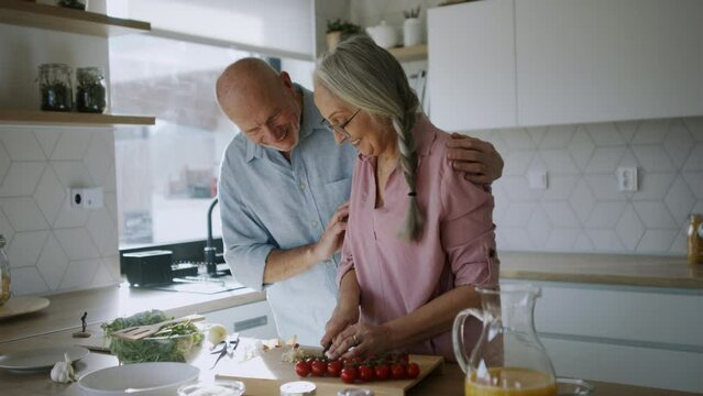 Happy senior couple cooking together at home.