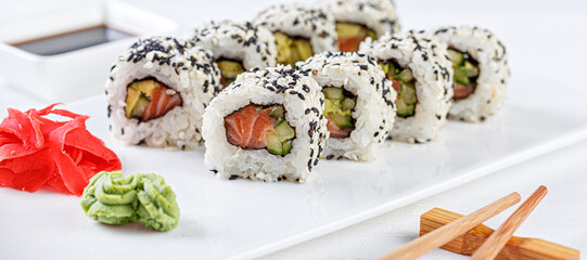 Sushi with salmon on a white plate with wasabi, ginger, soy, chopsticks on a white background