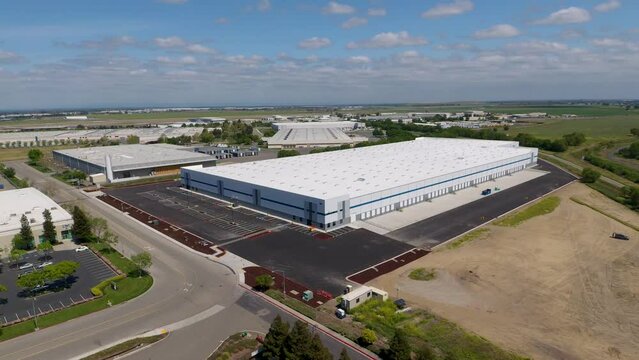 High orbiting drone shot of a new warehouse in an industrial area.