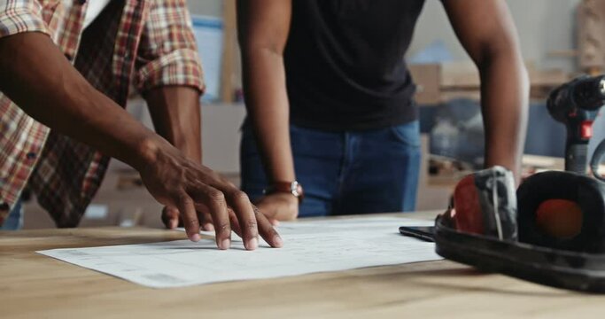 Close up shot of African carpenters discussing designs in carpentry factory