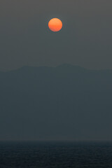 日本　山口県柳井市と愛媛県松山市を結ぶフェリーの船上から見える島々と霞んだ空に沈みゆく夕日