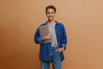 Young short-haired beautiful smiling woman in shirt with laptop