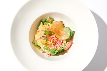 Elegant salad with crab meat, espuma sauce and lettuce on white table with harsh shadows. Green salad with crab and creamy sauce in summer menu. Aesthetic food. Seafood appetizer.
