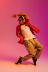 African man enjoying music and dancing isolated over gradient neon background