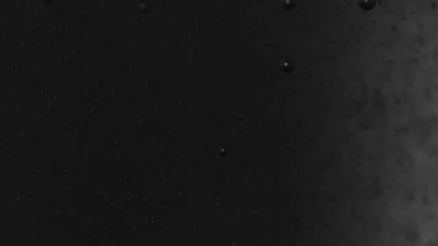 Dark abstract background with liquid with stationary bubbles and a stream of bubbles moving upwards. Fluid dynamics in a minimal and clean background in a dark variant. Moving liquids and fast bubbles