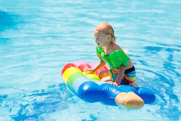 Fototapeta na wymiar Kids on inflatable float in swimming pool.