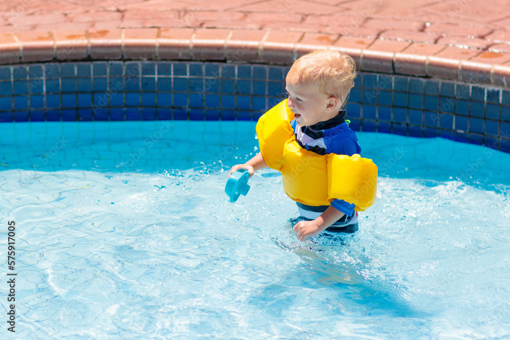 Wall mural baby with inflatable armbands in swimming pool.