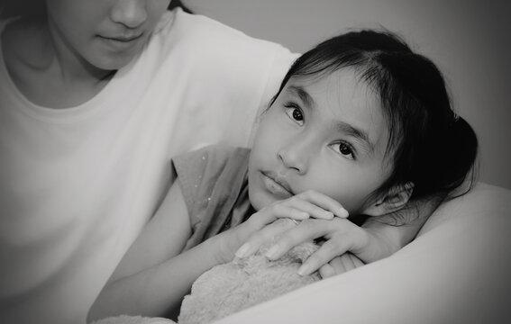 Black and white photo Sensitive asian daughter with a weak heart and an unhappy face, worried about something, with a caring mother at her side to help relieve stress.
