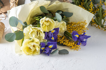 Spring bouquet of flowers. Irises, tulips, mimosa and eucalyptus. Yellow and blue flower. Bud...