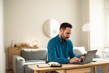 Fototapeta premium Busy male employee working over the laptop, sitting at the home office.