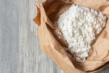 Plain white flour in a brown paper bag on grey wood. Eco friendly biodegradable recycle packaging