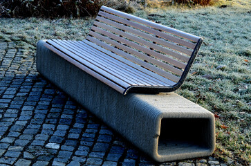 park bench has a concrete tube base flattened on the sides. the bench is printed on a 3d printer...