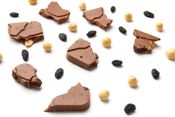 Pieces of chocolate with raisins and nuts on a white background.