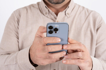 Using smartphone, close up shot of caucasian man using smartphone. Male hands holding modern mobile phone with three cameras. Messaging, browsing app, online shopping, social media concept idea.