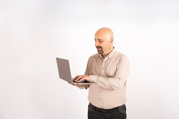 Working online, happy caucasian man holding laptop working online. Standing over isolated light gray background. Fingers on keyboard. Browsing internet, technology, office worker, remote job concept.