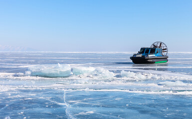 Frozen Baikal Lake on February sunny day. Tourists travel on the ice of the lake in an airboat to Olkhon Island. Ice trips along the Small Sea to Khoboy Cape. Winter ice trips and travel concept