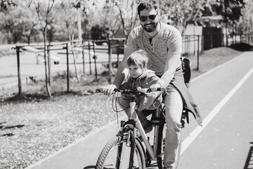 father and son cycling together on one bicycle along bike lane. Father's day concept. Image with selective focus