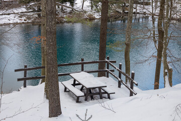 Snow covered wooden bench and table at Lame lake in Aveto Valley in winter time , in the hamlet of Rezzoaglio, province of Genoa, Italy.