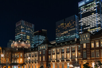 Fototapeta na wymiar 日本　東京都千代田区丸の内のライトアップされた赤レンガ作りの東京駅舎と高層ビル群の夜景