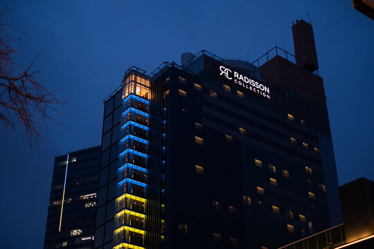 Tallinn, Estonia - 02.17.2023: Radisson Collection hotel in evening lights designed in Ukrainian flag colors. Radisson Collection hotel sign.