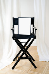 Black frame mockup on a black director cinema chair at minimalist studio interior. Poster frame mockup