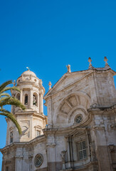 Detail of the Cathedral of La Santa Cruz of Cádiz with bell tower and large window flanked by statues of patron saints and concave shape above, SPAIN