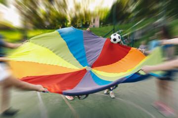 Kids Rainbow Umbrella Parachute Toy, Outdoor Cooperative Games For Children. Group of Children...