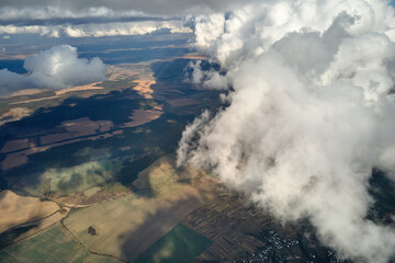 Aerial view at high altitude of earth covered with puffy cumulus clouds forming before rainstorm