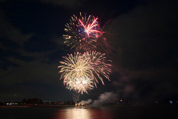 Aerial view of bright fireworks exploding with colorful lights over sea shore on US Independence day holiday