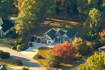 Aerial view of new family house between yellow trees in South Carolina suburban area in fall season. Real estate development in american suburbs