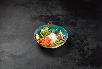 Poke bowl with salmon and vegetables on black concrete background. Ahi poke with salmon, rice,...