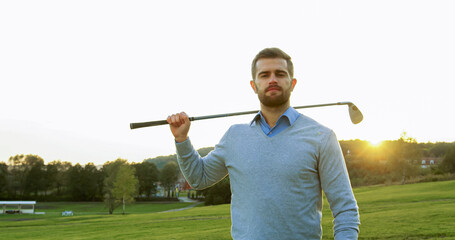 Portrait shot of attractive Caucasian man posing to the camera and putting a club on his shoulder,...