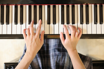 Close up of female hands playing a melody on piano