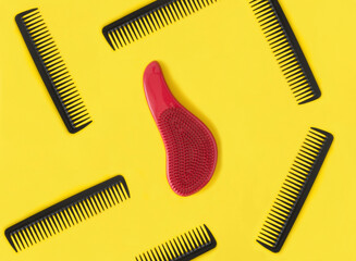 Black and red hair combs on the yellow background. Pattern. Flat lay. Top view.
