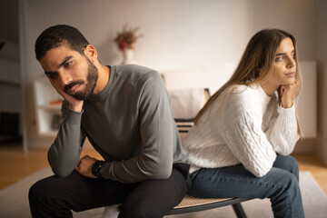 Sad offended unhappy young arabic man ignores european woman sit on sofa back to back
