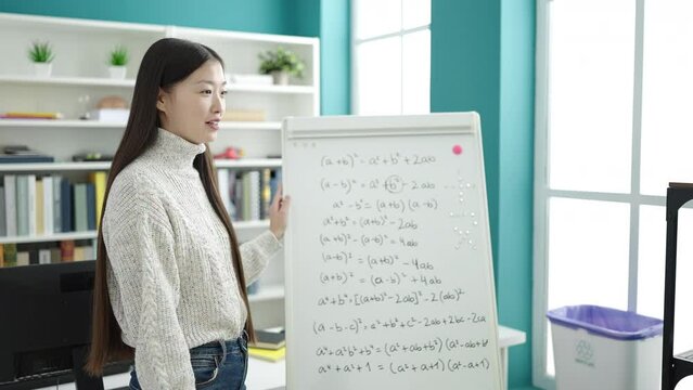 Young chinese woman student smiling confident explaining maths exercise at library university