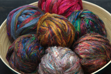 Colourful ball of recycled sari silk textile fibres from India, ready for spinning on a traditional...