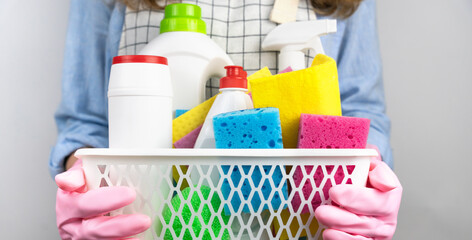 Woman's hands in gloves hold cleaning tools in basket. Cleaning service concept. Close-up. Selective focus.