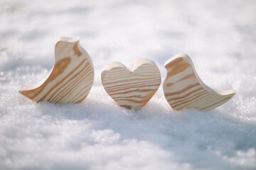 Beautiful decorative small wooden toy birds on white snow in winter. Easter, Spring decoration. Handmade wooden toys