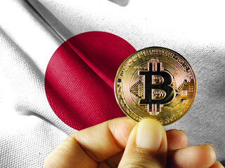 Hold the physical version of Bitcoin (the new virtual currency) and the Japanese flag. Japanese cryptocurrency and blockchain technology investor concept map 