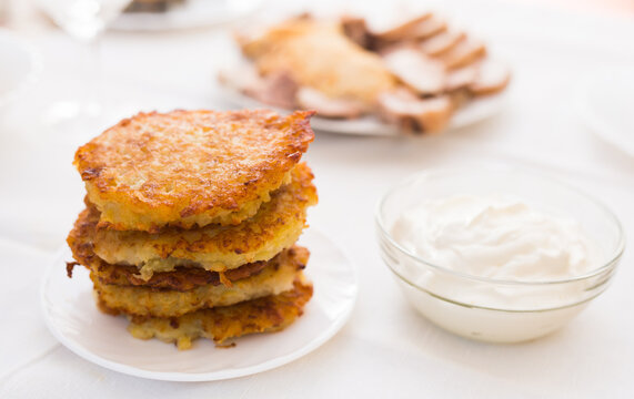 Potato pancakes with sour cream on white plate