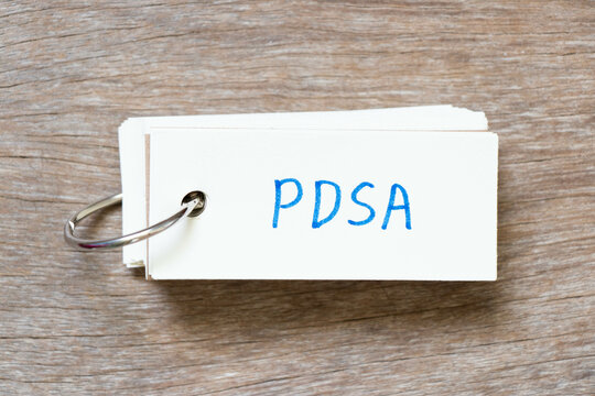 Flash card with handwriting in word PDSA (Abbreviation of plan do study act) on wood background