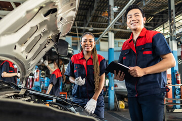 Engineer team checking under car condition on lifter in garage.Young auto mechanic in uniform is...