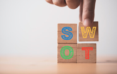 Hand putting S W O and T alphabet which print screen on wooden cube block for business marketing...