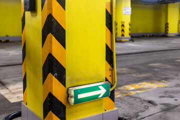 green traffic direction arrow sign on yellow underground parking post